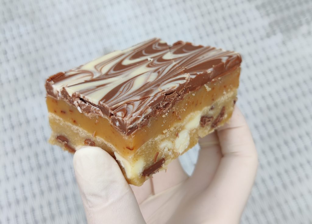 Millionaires cookie bars stacked on a board
